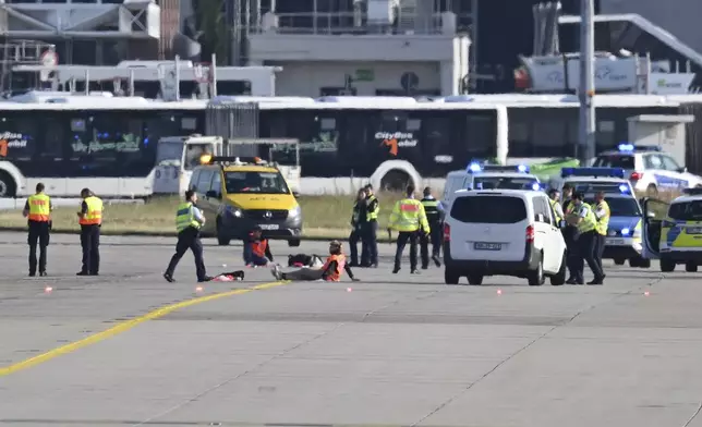 Emergency vehicles from the police, fire department and airport security are parked on the apron of Frankfurt Airport, where a few activists have taped themselves up, in Frankfurt, Germany, Thursday, July 25, 2024. (Arne Dedert/dpa via AP)