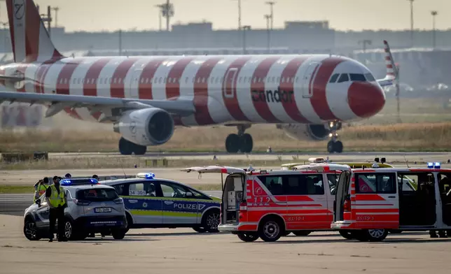 Emergency vehicles and police cars stand on a runway at the airport in Frankfurt, Germany, Thursday, July 25, 2024, after a few climate activists glued themselves to the ground blocking air traffic for several hours. (AP Photo/Michael Probst)