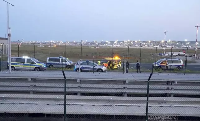 Police vehicles are parked not far from the tarmac at Frankfurt Airport, Thursday, July 25, 2024. Air traffic has been temporarily suspended due to an action by climate activists. ( Mike Seeboth/TNN/dpa via AP)