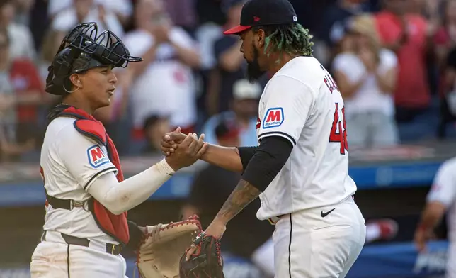 Cleveland Guardians' Bo Naylor, left, congratulates closer Emmanuel Clase after the third out in the ninth inning of a baseball game against the San Francisco Giants in Cleveland, Saturday, July 6, 2024. (AP Photo/Phil Long)