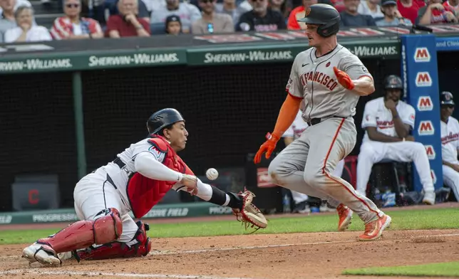 Cleveland Guardians' catcher Bo Naylor, left, misses the throw as San Francisco Giants' Matt Chapman slides safely into home plate during the fifth inning of a baseball game in Cleveland, Saturday, July 6, 2024. (AP Photo/Phil Long)