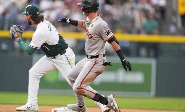 San Francisco Giants' Tyler Fitzgerald, front, slides into second base with an RBI double as Colorado Rockies second baseman Brendan Rodgers fields the throw in the fifth inning of a baseball game Saturday, July 20, 2024, in Denver. (AP Photo/David Zalubowski)