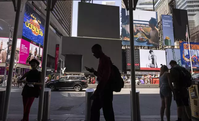 Pedestrians walk by blacked out screens due to a global technology outage in Times Square, Friday, July 19, 2024, in New York. (AP Photo/Yuki Iwamura)