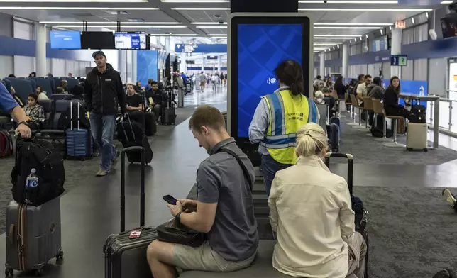 An IT field services technician works on software on an information display during a global technology outage near United Airlines gates at Chicago O'Hare International Airport, in Chicago, Friday, July 19, 2024. (AP Photo/Carolyn Kaster)