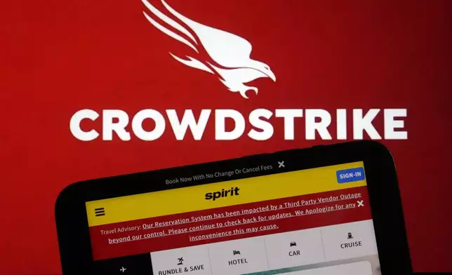 The logo for CrowdStrike and a Spirit Airlines webpage with a Travel Advisory about a third Party Outage impacting their Reservation System are shown on a computer screen and mobile phone screen, in New York, Friday, July 19, 2024. (AP Photo/Richard Drew)