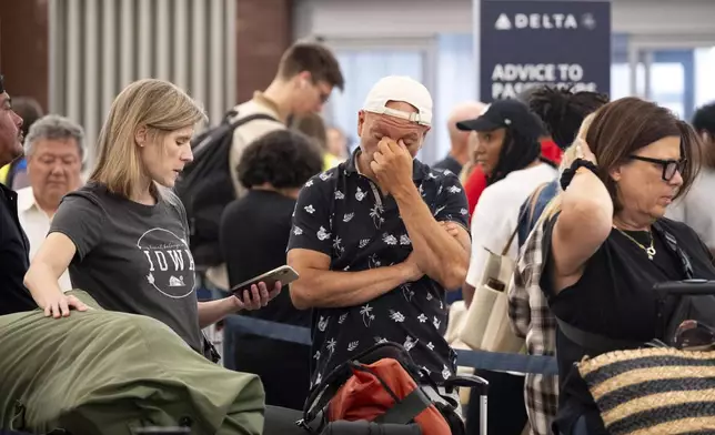 Tiffany McAllister and Andres Bernal try to rebook their flight to Iowa while at Hartsfield Jackson International Airport in Atlanta, Friday, July 19, 2024, as a major internet outage disrupts flights, banks, media outlets and companies across the world. (AP Photo/Ben Gray)