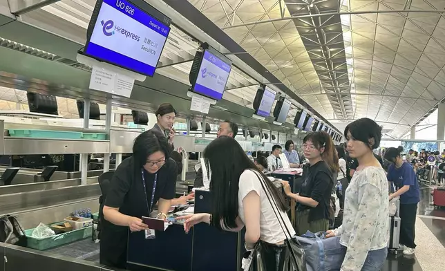 Passengers line up for manual check-in at the Hong Kong International Airport during a global technology outage in Hong Kong, Friday, July 19, 2024. (AP Photo/Kanis Leung)