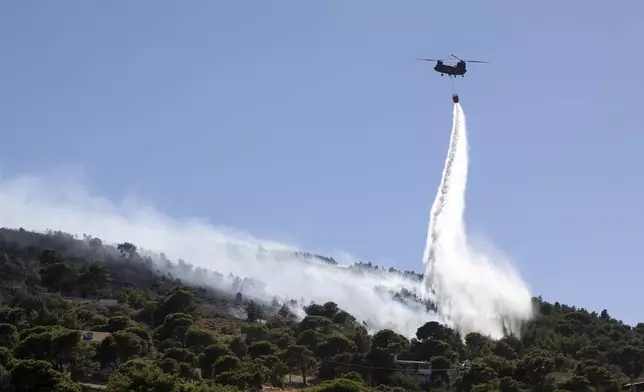 A firefighting helicopter throws water over a wildfire at Keratea area, southeast of Athens, Greece, Sunday, June 30, 2024. (AP Photo/Yorgos Karahalis)