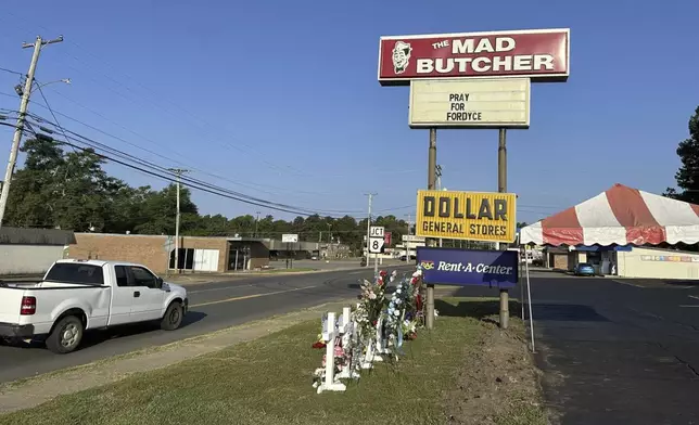 Memorials sit by the parking lot of the Mad Butcher grocery store in Fordyce, Ark., Tuesday, July 2, 2024. The store reopened 11 days after a shooter killed four people and injured 10 others in the store and its parking lot. (AP Photo/Andrew DeMillo)