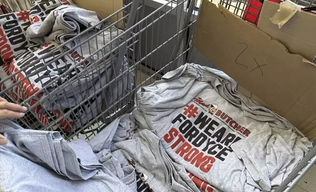 A stack of shirts being handed out to customers sits in a shopping cart at the Mad Butcher grocery store in Fordyce, Ark., Tuesday, July 2, 2024. The grocery store reopened on Tuesday, 11 days after a shooter killed four people and injured 10 others in in the store and its parking lot. (AP Photo/Andrew DeMillo)