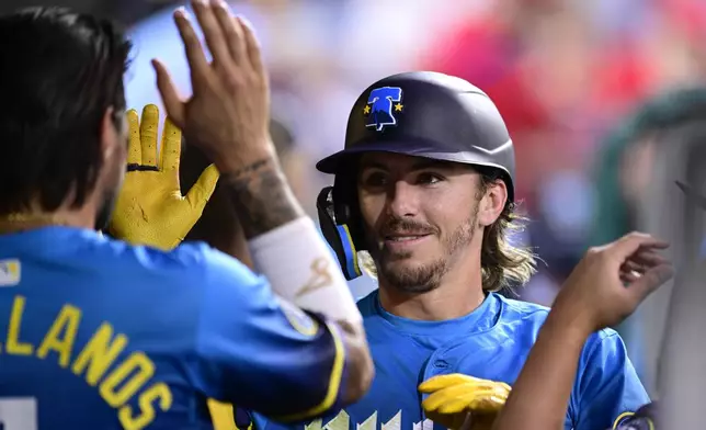 Philadelphia Phillies' Bryson Stott, right, celebrates with teammates in the dugout after hitting a solo home run off Cleveland Guardians' Ben Lively during the fifth inning of a baseball game, Friday, July 26, 2024, in Philadelphia. (AP Photo/Derik Hamilton)