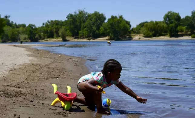 A young girl plays on the sand by the river in Sacramento, Calif., Tuesday, July 2, 2024. Swaths of California sweltered Tuesday, and things were only expected to get worse during the Fourth of July holiday week for parts of the United States with nearly 90 million people under heat alerts. (AP Photo/Terry Chea)