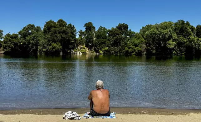 A man cools off by the river in Sacramento, Calif., Tuesday, July 2, 2024. Swaths of California sweltered Tuesday, and things were only expected to get worse during the Fourth of July holiday week for parts of the United States with nearly 90 million people under heat alerts. (AP Photo/Terry Chea)