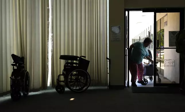 Sherri Thompson, with her chihuahua 14-year-old Kiwahi, arrives at the Cook Plaza cooling center on Friday, July 5, 2024, in Gresham, Ore. Thompson has lived in her car for three years, and can only run its air conditioning for about 20 minutes at a time as it causes the engine to overheat. Thompson said the high temperatures prompted health concerns, as she had been hospitalized for a heat stroke in the past. A heat wave is spreading across Wester U.S., the national Weather Service said, sending many residents in search of a cool haven from the dangerously high temperatures. (AP Photo/Jenny Kane)