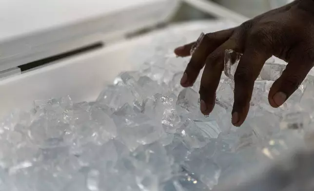 Ty Brown, with Cultivate Initiatives, puts ice over bottles of water as workers set up the Cook Plaza cooling center on Friday, July 5, 2024, in Gresham, Ore. A heat wave is spreading across Wester U.S., the national Weather Service said, sending many residents in search of a cool haven from the dangerously high temperatures. (AP Photo/Jenny Kane)