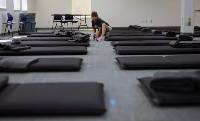 Doll Crain, with Cultivate Initiatives, marks off places for beds as workers set up the Cook Plaza cooling center on Friday, July 5, 2024, in Gresham, Ore. A heat wave is spreading across Wester U.S., the national Weather Service said, sending many residents in search of a cool haven from the dangerously high temperatures. (AP Photo/Jenny Kane)