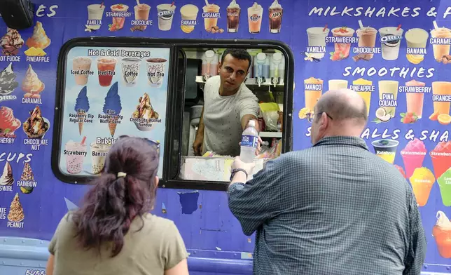 Wesam Horni, center, sells water on the National Mall near the U.S. Capitol, Friday, July 5, 2024, in Washington. (AP Photo/Mariam Zuhaib)