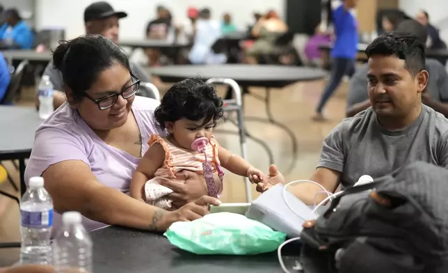 FILE - Keyla Herrera entertains her eight-month-old daughter, Emma, with a movie on her cell phone next to her husband, Edgar, as they sat inside of the cooling center set up inside of Sunnyside Health and Multi-Service Center on Wednesday, July 10, 2024. As of Thursday, July 18, most Houston residents finally had electricity after more than a week of widespread outages. (Karen Warren/Houston Chronicle via AP, File)