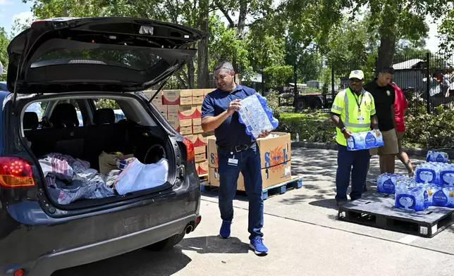 FILE - Volunteers hand out water at a distribution station in Houston, Wednesday, July 10, 2024. As of Thursday, July 18, most Houston residents finally had electricity after more than a week of widespread outages. (AP Photo/Maria Lysaker, File)