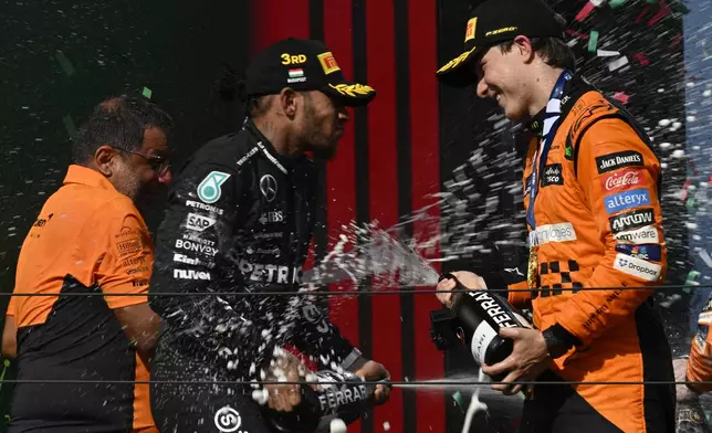 McLaren driver Oscar Piastri of Australia, right, celebrates with third placed Mercedes driver Lewis Hamilton of Britain on the podium after winning the Hungarian Formula One Grand Prix race at the Hungaroring racetrack in Mogyorod, Hungary, Sunday, July 21, 2024. (AP Photo/Denes Erdos)