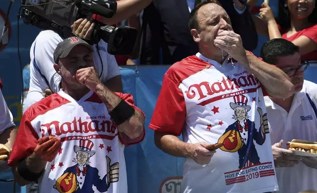FILE - Geoffrey Esper, left, and Joey Chestnut, right, compete during the men's competition of Nathan's Famous July Fourth hot dog eating contest, July 4, 2019, in New York's Coney Island. The annual Nathan’s Famous Fourth of July hot dog eating contest will see a slate of competitive eaters wolf down as many franks as they can in New York City on Thursday, July 4, 2024. (AP Photo/Sarah Stier, File)