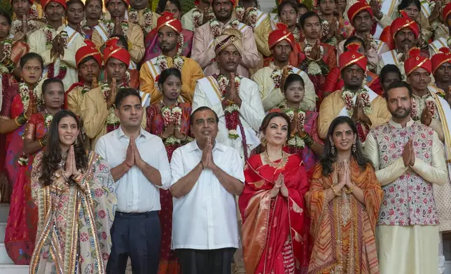 FILE - Chairman of Reliance Industries Limited Mukesh Ambani, third left, poses with his family members and underprivileged couples during a mass wedding organized by him as the part of pre-wedding celebrations of his youngest son, Anant Ambani, in Mumbai, India, Tuesday, July 2, 2024. (AP Photo/Rafiq Maqbool, File)