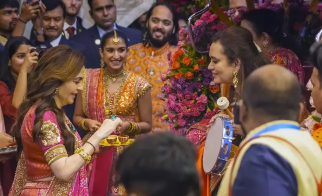 FILE - Nita Ambani, left, wife of Mukesh Ambani along with his son Anant Ambani, center right, and his fiancée Radhika Merchant, second left, greet guests during their pre-wedding ceremony at their residence in Mumbai, India, Wednesday, July 3, 2024.(AP Photo/Rafiq Maqbool, File)