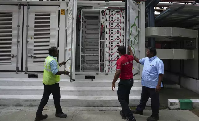 Team leader K. Sridhar, center, closes the doors after a routine check of lithium ion batteries for a 500-kilowatt battery energy storage system inside the Hindustan Coca-Cola Beverages factory in Thiruvallur District, on the outskirts of Chennai, India, Tuesday, July 16, 2024. (AP Photo/Mahesh Kumar A.)