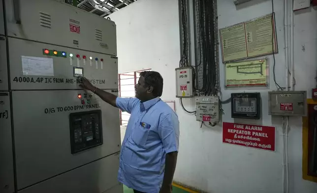 Electrician A. Prakash checks the parameter of the output breaker of a 500-kilowatt battery energy storage system inside the Hindustan Coca-Cola Beverages factory in Thiruvallur district, on the outskirts of Chennai, India, Tuesday, July 16, 2024. (AP Photo/Mahesh Kumar A.)