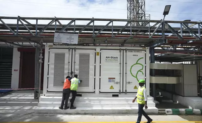 Team leader K. Sridhar, center, closes the doors after a routine check of lithium ion batteries of 500-kilowatt battery energy storage system inside the Hindustan Coca-Cola Beverages factory in Thiruvallur District, on the outskirts of Chennai, India, Tuesday, July16, 2024. (AP Photo/Mahesh Kumar A.)