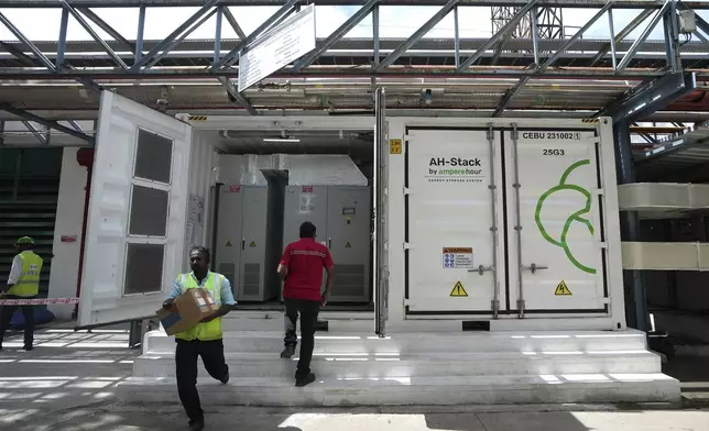 A worker walks in front of the 500-kilowatt battery energy storage system inside the Hindustan Coca-Cola Beverages factory in Thiruvallur district, on the outskirts of Chennai, India, Tuesday, July 16, 2024. (AP Photo/Mahesh Kumar A.)