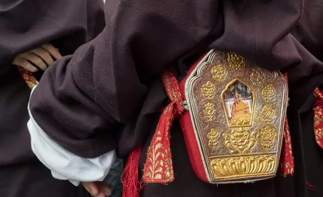 An exiled Tibetan wears an amulet with a portrait of Tibetan spiritual leader the Dalai Lama before he performs a traditional dance at an event to celebrate the 89th birthday of the spiritual leader at the Tsuglakhang temple in Dharamshala, India, Saturday, July 6, 2024. (AP Photo/Ashwini Bhatia)