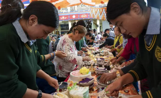 Exiled Tibetan school children and volunteers put cakes on paper plates before distributing them to a gathering at an event to celebrate the 89th birthday of Tibetan spiritual leader the Dalai Lama at the Tsuglakhang temple in Dharamshala, India, Saturday, July 6, 2024. (AP Photo/Ashwini Bhatia)