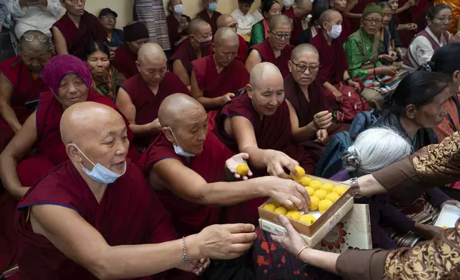 A volunteer distributes Indian sweets to exile Tibetan Buddhist nuns at an event to celebrate the 89th birthday of Tibetan spiritual leader the Dalai Lama at the Tsuglakhang temple in Dharamshala, India, Saturday, July 6, 2024. (AP Photo/Ashwini Bhatia)