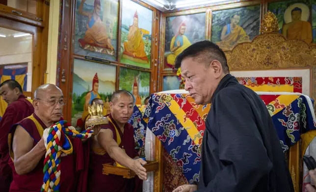 Penpa Tsering, President of Central Tibetan Administration, right, pays his respects in front of a ceremonial chair of Tibetan spiritual leader the Dalai Lama at an event to celebrate the 89th birthday of the spiral leader at the Tsuglakhang temple in Dharamshala, India, Saturday, July 6, 2024. (AP Photo/Ashwini Bhatia)