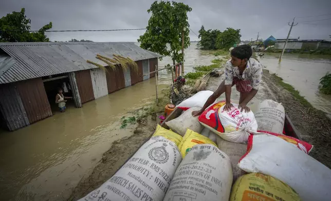 A flood affected person loads sacks of rice on a vehicle to transport to a safer place from his submerged house in Sildubi village in Morigaon district in the northeastern state of Assam, India, Tuesday, July 2, 2024. Floods and landslides triggered by heavy rains have killed more than a dozen people over the last two weeks in India's northeast. (AP photo/Anupam Nath)