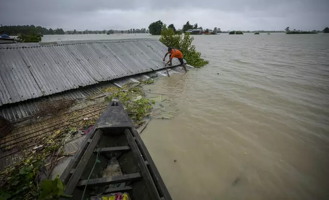 A flood victim tries to fix a tin roof of his submerged house in Sildubi village in Morigaon district in the northeastern state of Assam, India, Tuesday, July 2, 2024. Floods and landslides triggered by heavy rains have killed more than a dozen people over the last two weeks in India's northeast. (AP photo/Anupam Nath)