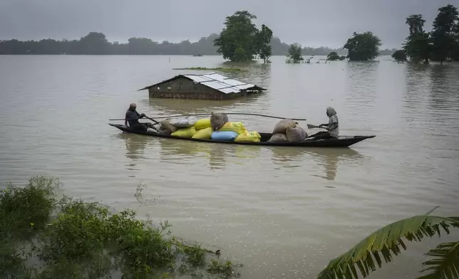 Flood affected people travel with sacks of rice in a country boat through flood waters in Mayong village in Morigaon district in the northeastern state of Assam, India, Tuesday, July 2, 2024. Floods and landslides triggered by heavy rains have killed more than a dozen people over the last two weeks in India's northeast. (AP photo/Anupam Nath)