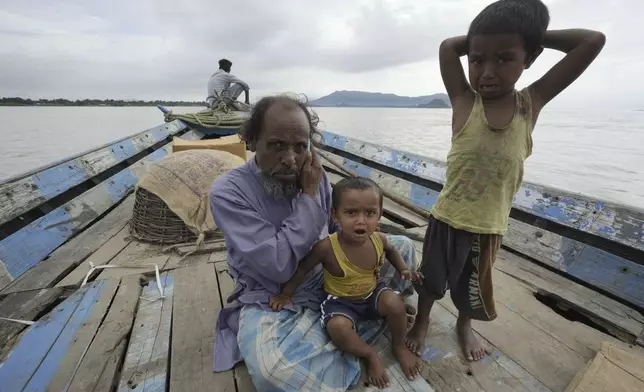 Kamaluddin speaks on the phone, with his son Azrahul Islam, right, and daughter Arohi Jannat by his side, after his wife Jahanara Khatoon delivered a baby on the boat, over the River Brahmaputra, in the northeastern Indian state of Assam, Wednesday, July 3, 2024. (AP Photo/Anupam Nath)