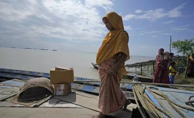 25-year-old Jahanara Khatoon, who is at full-term pregnancy, boards a boat on her way to a health centre, in Sandoh Khaiti Char, in the northeastern Indian state of Assam, Wednesday, July 3, 2024. (AP Photo/Anupam Nath)