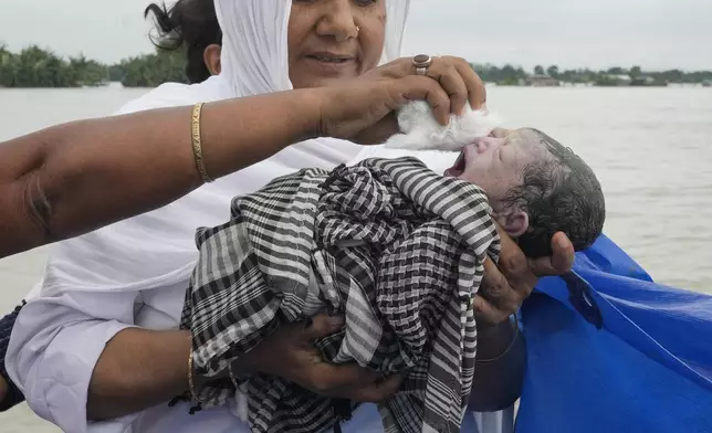 Diluwara Begum, a midwife, holds up a newborn baby after helping in her delivery on a boat over the River Brahmaputra, in the northeastern Indian state of Assam, Wednesday, July 3, 2024. (AP Photo/Anupam Nath)