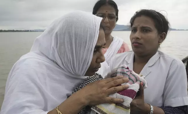 Diluwara Begum, a midwife, whispers prayers into the ear of a newborn baby she helped deliver on a boat over the River Brahmaputra, in the northeastern Indian state of Assam, Wednesday, July 3, 2024. (AP Photo/Anupam Nath)