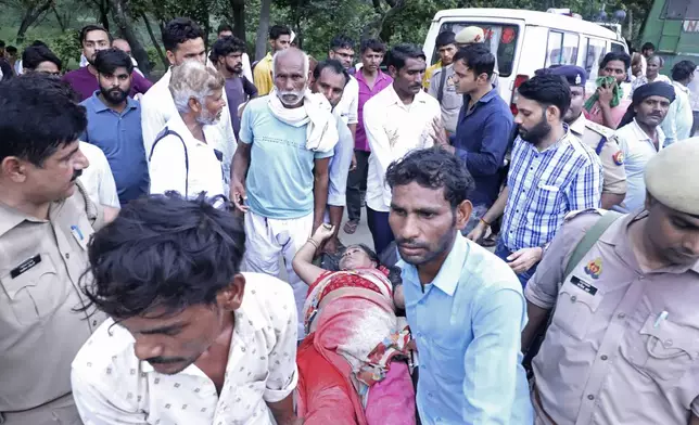 People carry a woman on a stretcher outside the Sikandrarao hospital in Hathras district about 350 kilometers (217 miles) southwest of Lucknow, India, Tuesday, July 2, 2024. Thousands of people at a religious gathering in India rushed to leave a makeshift tent, setting off a stampede Tuesday that killed more than hundred people and injured scores. (AP Photo/Manoj Aligadi)