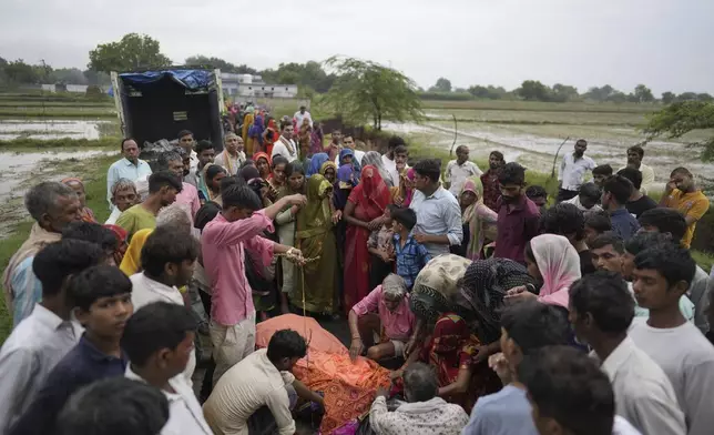 Family members and neighbors perform the last rites of Savitri Devi, 50, who died during a stampede, in Ramnagar, in the northern Indian state of Uttar Pradesh, Wednesday, July 3, 2024. Devi was among more than 120 people who died in a stampede last week at a religious festival in northern India, as the faithful surged toward the preacher and chaos ensued among the attendees. (AP Photo/Rajesh Kumar Singh)