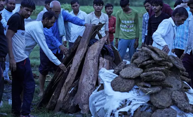 Ajay Kumar, left, stands near the funeral pyre of his mother Savitri Devi, 50, who died during a stampede, in Ramnagar, in the northern Indian state of Uttar Pradesh, Wednesday, July 3, 2024. "My parents believed that Babaji would lift all our burdens," Kumar said, while adding that he also went to religious gatherings of the Baba because it became a family tradition. (AP Photo/Rajesh Kumar Singh)