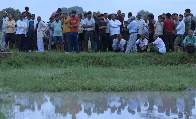 Villagers watch the cremation of Savitri Devi, 50, who died during a stampede, in Ramnagar, in the northern Indian state of Uttar Pradesh, Wednesday, July 3, 2024. Devi was among more than 120 people who died in a stampede last week at a religious festival in northern India, as the faithful surged toward the preacher and chaos ensued among the attendees. (AP Photo/Rajesh Kumar Singh)