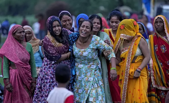 Bharti Kumari, centre, and Sonam, centre right behind Kumari, weep as the body of their mother Savitri Devi, 50, who died during a stampede, is carried for cremation in Ramnagar, in the northern Indian state of Uttar Pradesh, Wednesday, July 3, 2024. Devi was among more than 120 people who died in a stampede last week at a religious festival in northern India, as the faithful surged toward the preacher and chaos ensued among the attendees. (AP Photo/Rajesh Kumar Singh)