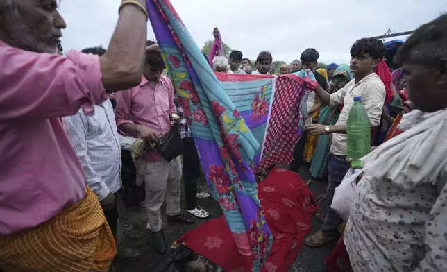 Family members and neighbors perform the last rites of Savitri Devi, 50, who died during a stampede, in Ramnagar, in the northern Indian state of Uttar Pradesh, Wednesday, July 3, 2024. Devi was among more than 120 people who died in a stampede last week at a religious festival in northern India, as the faithful surged toward the preacher and chaos ensued among the attendees. (AP Photo/Rajesh Kumar Singh)