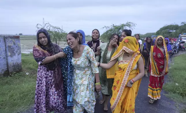 Bharti Kumari, second left, and Sonam, centre in green, weep as the body of their mother Savitri Devi, 50, who died during a stampede, is carried for cremation in Ramnagar, in the northern Indian state of Uttar Pradesh, Wednesday, July 3, 2024. Devi was among more than 120 people who died in a stampede last week at a religious festival in northern India, as the faithful surged toward the preacher and chaos ensued among the attendees. (AP Photo/Rajesh Kumar Singh)