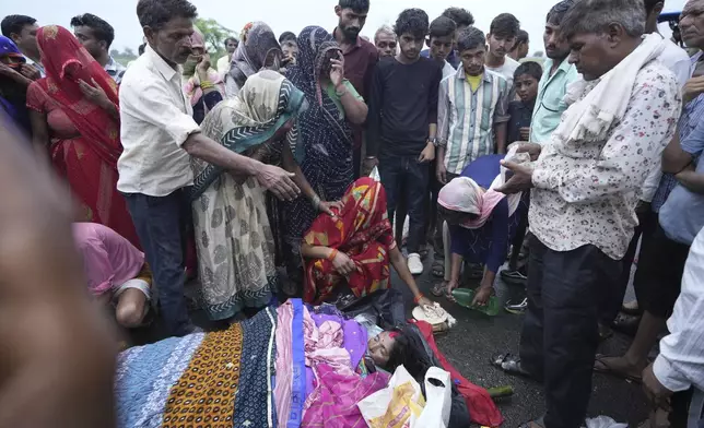 Family members and neighbors perform the last rites of Savitri Devi, 50, who died during a stampede, in Ramnagar, in the northern Indian state of Uttar Pradesh, Wednesday, July 3, 2024. Devi was among more than 120 people who died in a stampede last week at a religious festival in northern India, as the faithful surged toward the preacher and chaos ensued among the attendees. (AP Photo/Rajesh Kumar Singh)